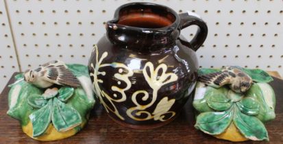 A slip glazed terracotta jug with butterfly design, 17cm high together with a pair of majolica wall