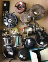 A box containing a selection of vintage fly reels, boat reels wooden and brass and a fisherman's