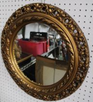 A modern circular wall mirror with gilded frame