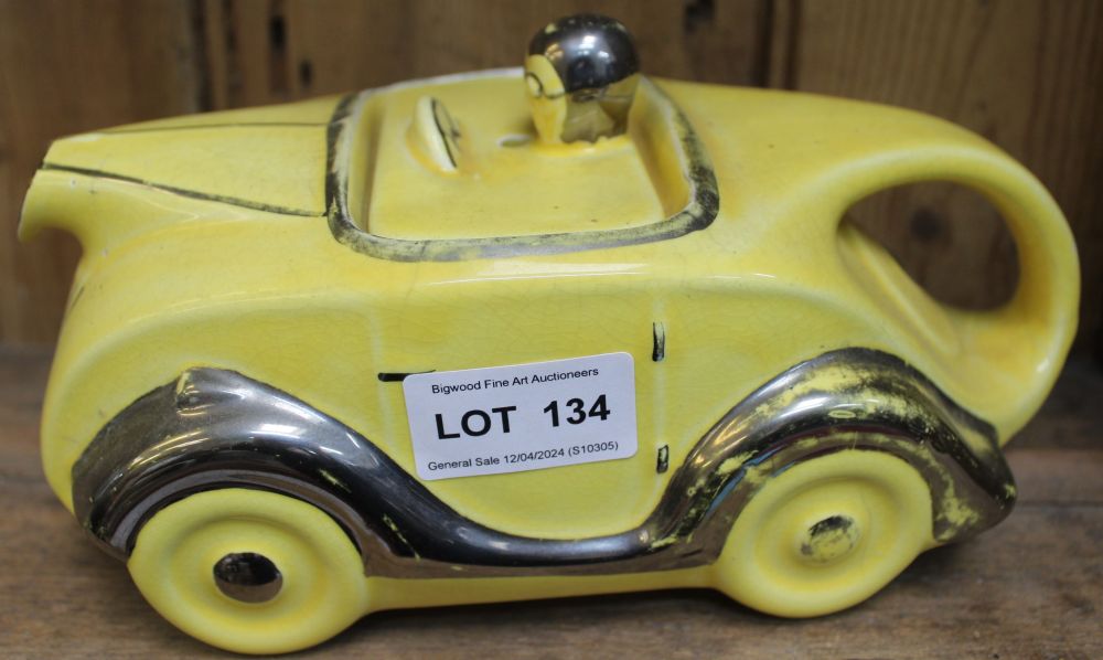 An Art Deco design sports car ceramic teapot, yellow glaze with silvered detail, number plate "OK T4