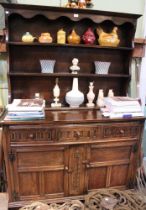A dark wood dresser with three in-line drawers over two cupboard doors and three shelf plate rack