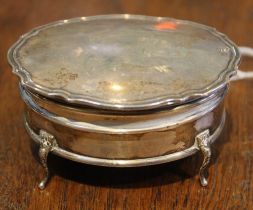 A silver trinket or ring box, oval shape, hinged lid reveals blue fabric interior, raised on