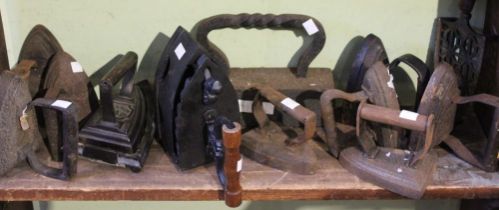 A shelf of vintage cast iron flat and smoothing irons