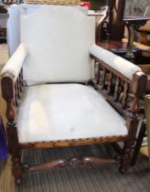 An early 20th century oak framed cream upholstered armchair with Tudor Rose stretcher