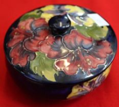 A Moorcroft pottery lidded bowl, tube lined and painted Hibiscus design on a blue ground, 12cm diame