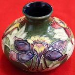 A Moorcroft pottery vase of squat form, tube lined and painted Lily design on a green ground, 10.5cm