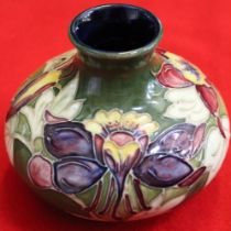 A Moorcroft pottery vase of squat form, tube lined and painted Lily design on a green ground, 10.5cm