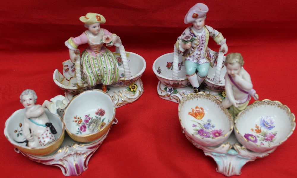 Four 19th century porcelain salts, including a pair of Meissen ones, modelled as figures sat upon ba