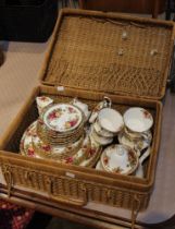 A wicker picnic basket housing a collection of Old Country Roses china