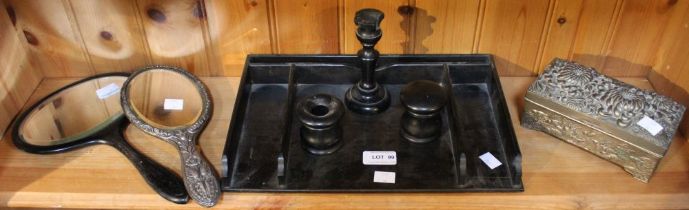 A shelf containing an ebonised wood desktop tray, two hand mirrors and a metal box