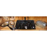 A shelf containing an ebonised wood desktop tray, two hand mirrors and a metal box