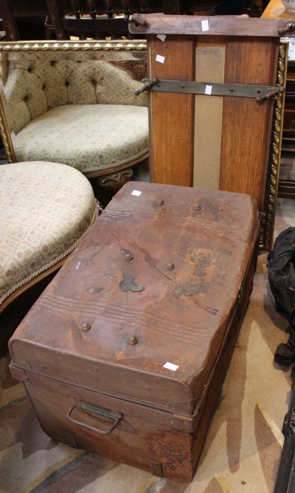 A tin trunk with a vintage wooden trouser press and a brass and wooden magazine rack