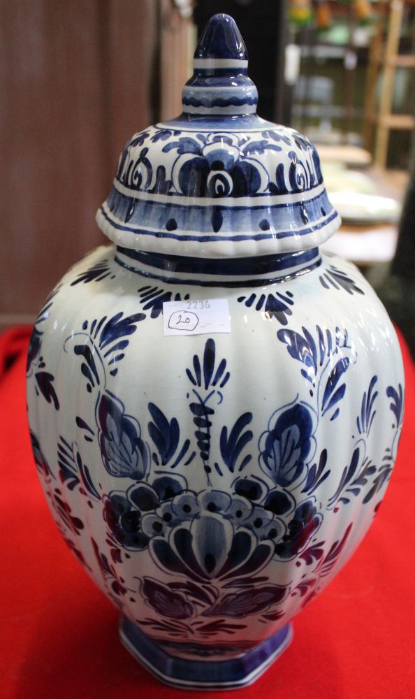 A hand painted Delft glazed earthenware vase of fluted form, having domed cover, cobalt blue floral