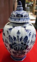 A hand painted Delft glazed earthenware vase of fluted form, having domed cover, cobalt blue floral