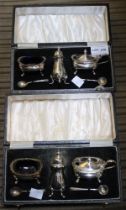 Two individually cased silver condiment sets of Georgian design, comprising pepper pots, salts and l