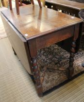 An oak drop leaf early 20th century dining table on barley twist legs with stretcher below