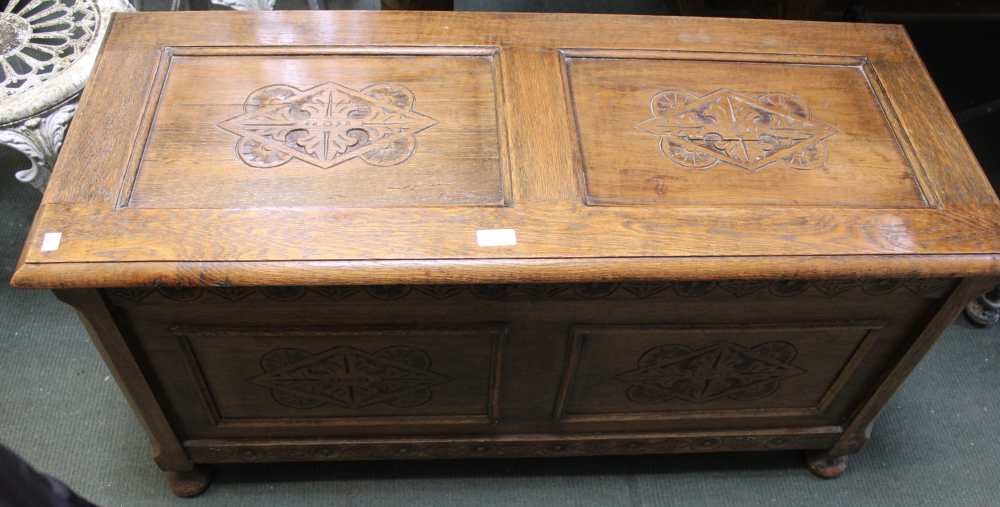 A 20th century oak trunk with carved panels to front and lid