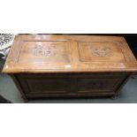 A 20th century oak trunk with carved panels to front and lid