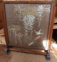 A Japanese silk embroidered panel, Wisteria and birds set in wood fire screen