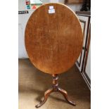 A 19th century mahogany oval snap top wine table, raised on turned stem with tripod supports