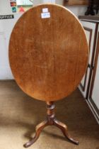 A 19th century mahogany oval snap top wine table, raised on turned stem with tripod supports
