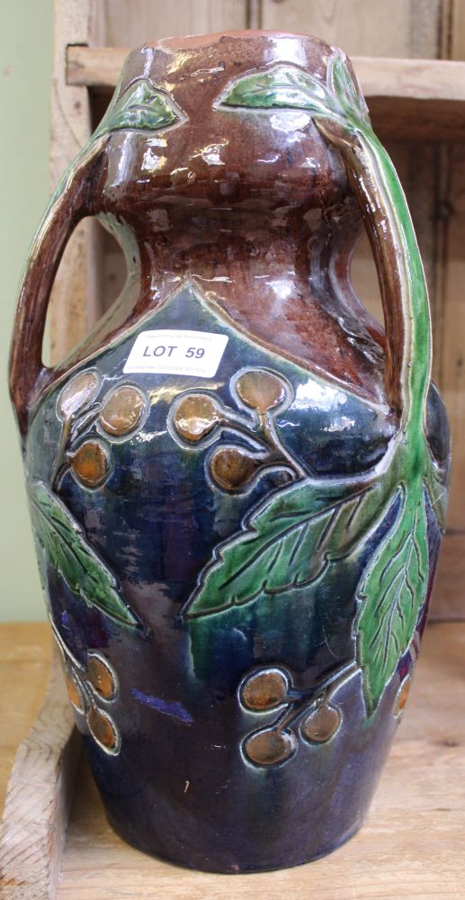 A glazed pottery vase in the manner of Christopher Dresser, having three sprig handles, incised frui