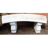 A curved concrete garden bench on twin supports
