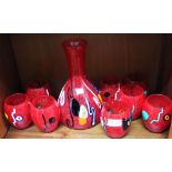 A Murano glass table set, comprising carafe and eight matching tumblers, red splatter ground with mu