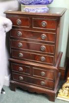 A reproduction dark wood chest on chest of small proportions
