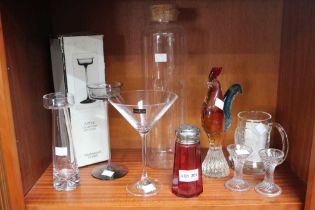 A shelf containing a collection of glass ware, including a Murano cockerel, Wedgwood crystal candle