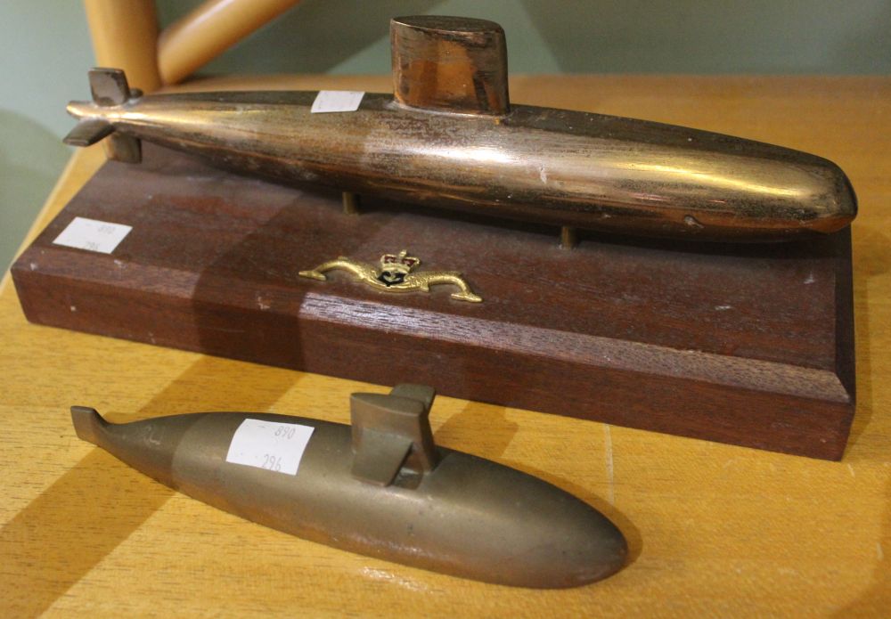 A brass model of a submarine mounted on a wooden plinth with a Royal Navy submarine emblem with