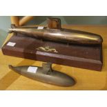 A brass model of a submarine mounted on a wooden plinth with a Royal Navy submarine emblem with