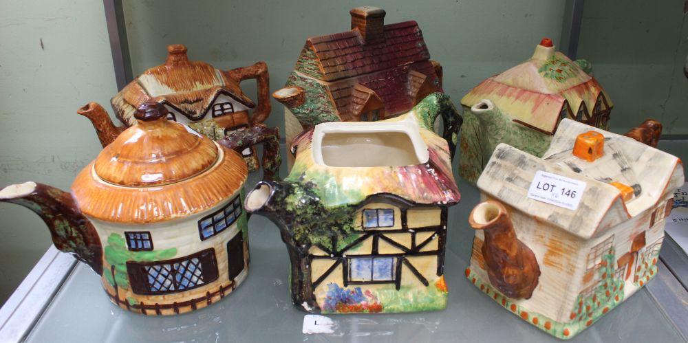 A collection of six pottery tea pots in the form of cottages, one round, all polychrome painted (one