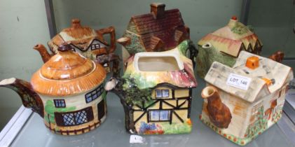 A collection of six pottery tea pots in the form of cottages, one round, all polychrome painted (one