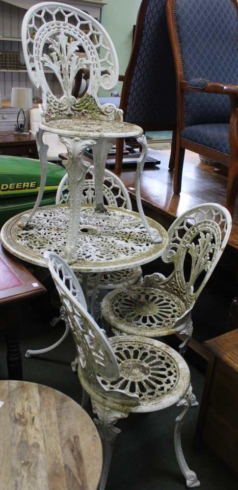 A well weathered cast metal garden table and four chairs