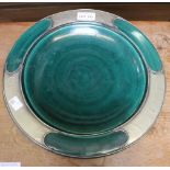 An Arts and Crafts design green glazed plate with pewter mounts, in a "Liberty" style 30cm diameter