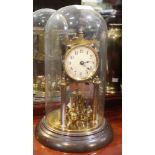An early 20th century brass Anniversary clock, with four ball pendulum and key, under glass dome, ov