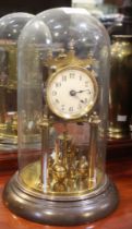 An early 20th century brass Anniversary clock, with four ball pendulum and key, under glass dome, ov
