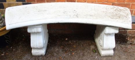 A curved concrete garden bench on twin supports