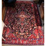A Persian design carpet with stylised floral decoration on a dark blue ground, deeply bordered