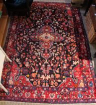 A Persian design carpet with stylised floral decoration on a dark blue ground, deeply bordered
