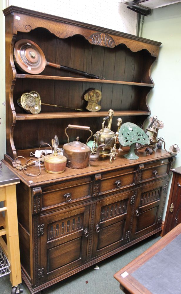 A dark oak Old Charm style dresser with three in-line drawers over three cupboard doors and plate