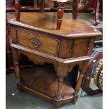 An oak corner table with single drawer and open under tier