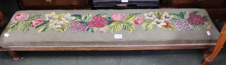 An oak framed long low foot stool with tapestry top