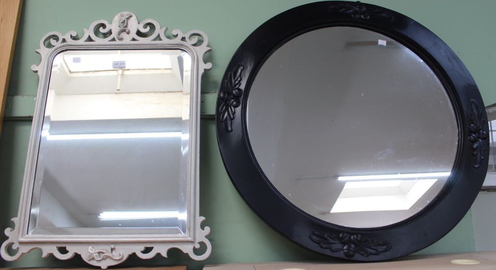 A large circular black painted wall mirror with a smaller white fancy framed mirror