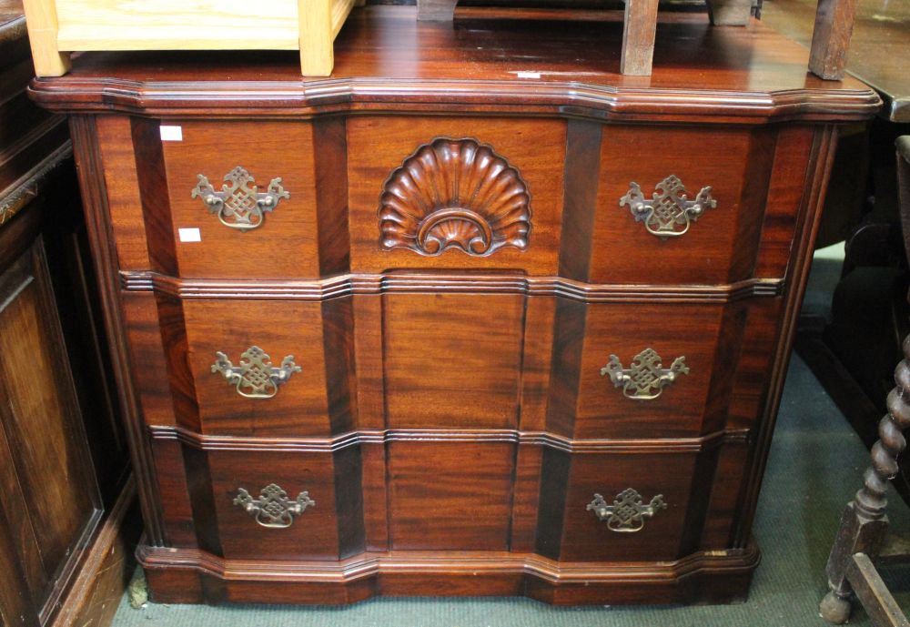 A reproduction set of hard wood chest of three drawers with brass drop handles and carved