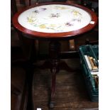 A low tripod wine table with claw caster feet and silk upholstered top beneath glass