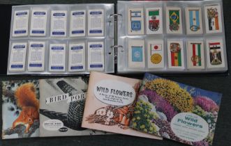 An album containing a quantity of vintage cigarette cards, together with four tea card albums