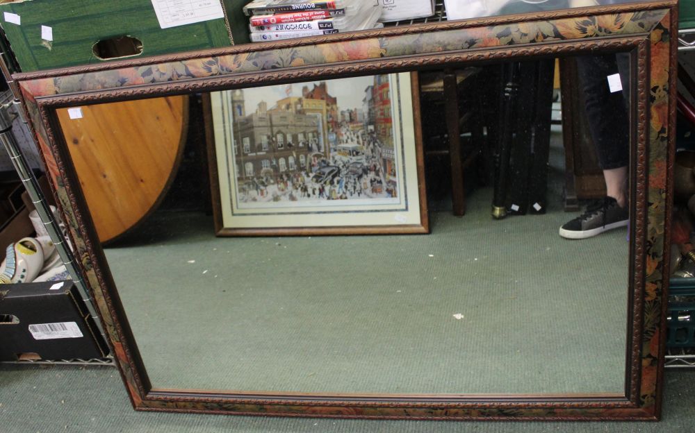 A large wall mirror with floral decorated frame