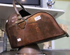 A copper coal scuttle with a selection of logs